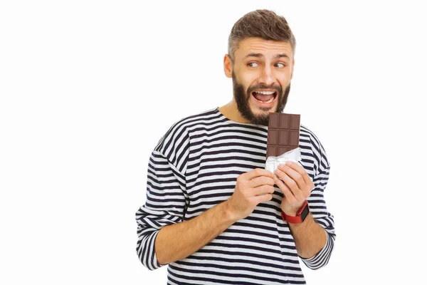 Nice handsome man biting a chocolate bar — Stock Photo, Image