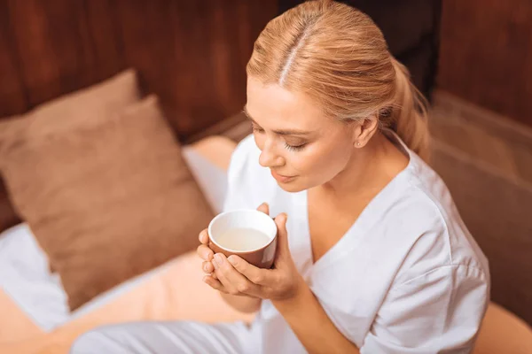 Mujer rubia agradable mirando la taza —  Fotos de Stock