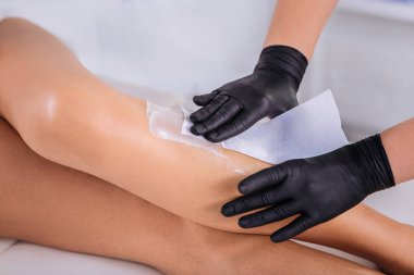 Epilasyon balmumu uzakta striping eldiven giymiş ustanın yakın çekim