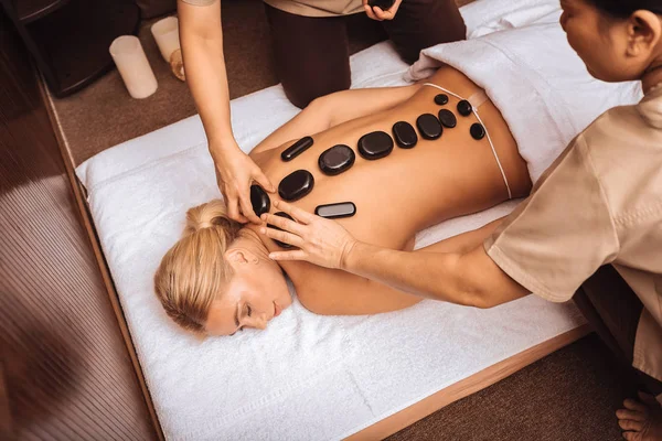 Profesional asiático masajistas poner Caliente piedras en hembra espalda —  Fotos de Stock