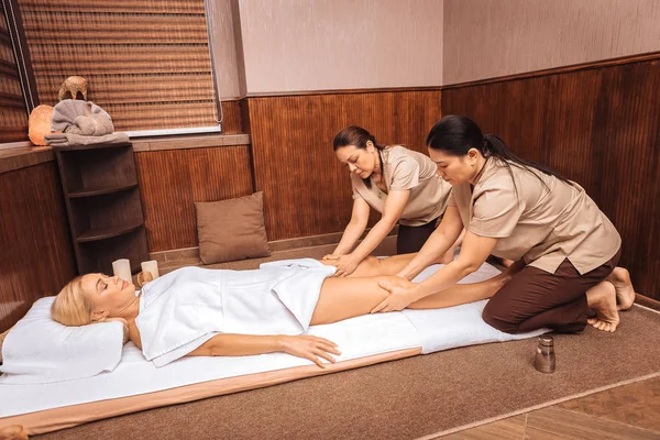 Masajistas tailandeses calificados masajeando piernas femeninas — Foto de Stock