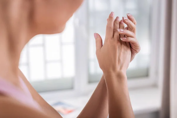 Beautiful woman with sensitive skin putting some cream on her hands