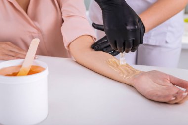 Balmumu Depilasyon onun koluna sahip bej bluz giyen kadın