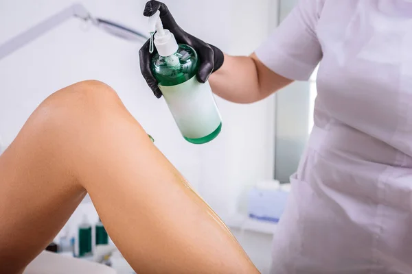 Depilação mestre vestindo uniforme branco usando algum gel de aloés — Fotografia de Stock