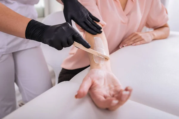 Hårborttagningsprodukter master bär vita uniform att göra hårborttagning arm — Stockfoto