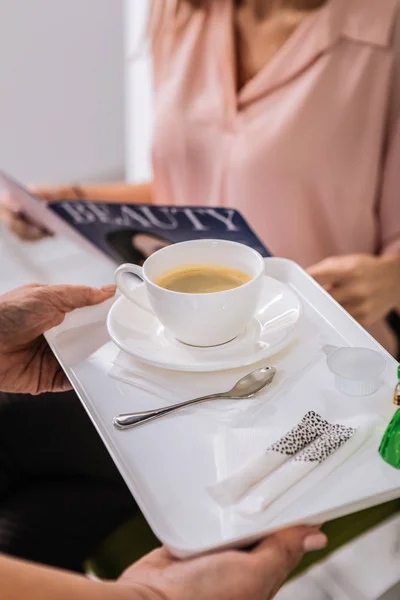 Gerente cuidadoso trayendo un poco de café para el cliente esperando en el salón de belleza — Foto de Stock