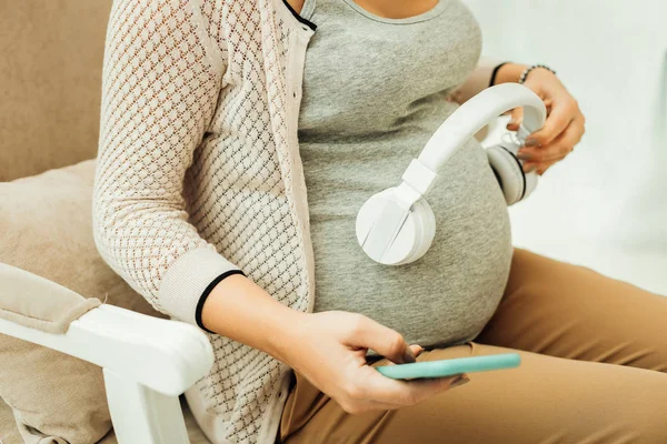 Mulher grávida criando uma lista de reprodução para seu futuro bebê — Fotografia de Stock