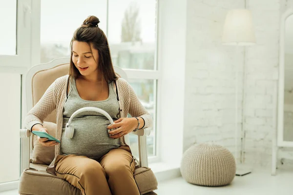 Женщина, заставляющая будущего ребенка слушать музыку — стоковое фото
