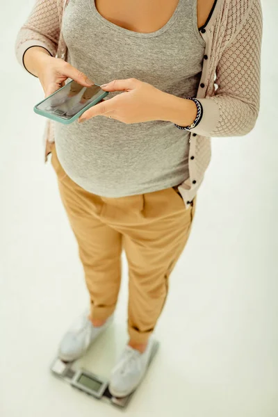 Беременная женщина использует мобильное приложение для контроля веса — стоковое фото