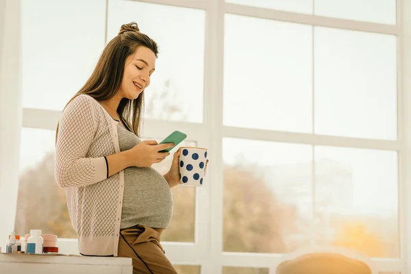 Gravid kvinna dricka te och surfa på internet — Stockfoto