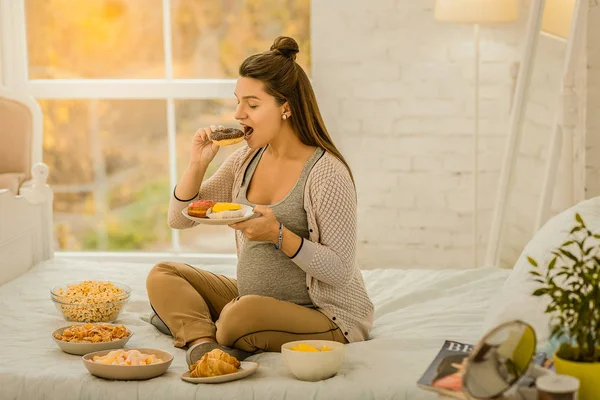 Frau isst während der Schwangerschaft viele Süßigkeiten — Stockfoto