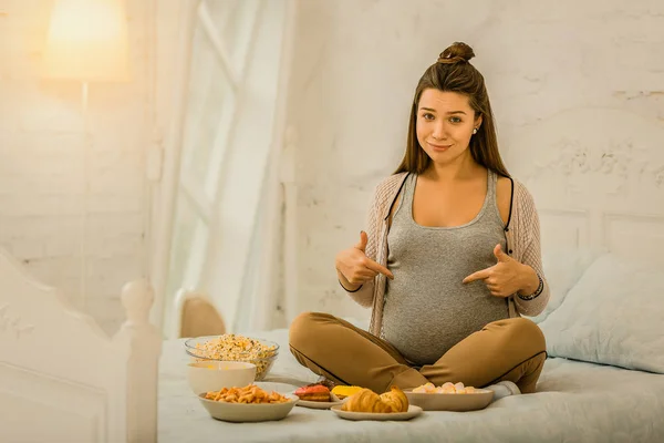 Mujer embarazada comiendo una gran cantidad de alimentos diferentes — Foto de Stock