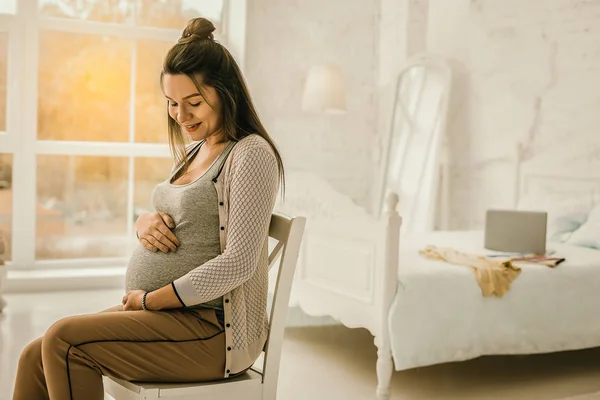 Vrouw verwacht een baby zit in de slaapkamer — Stockfoto