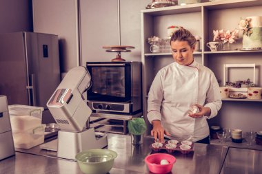 Onu mutfakta ayakta profesyonel kadın aşçı