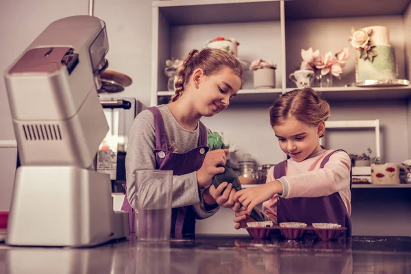 Positivo lindo niñas tratando de preparar muffins —  Fotos de Stock