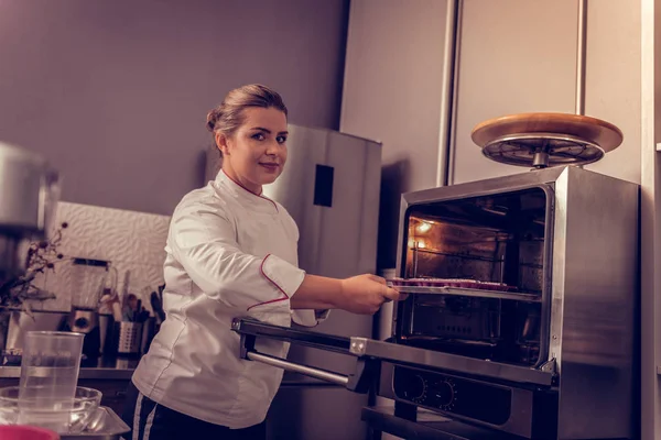 Encantada chef de pastelería femenina usando el horno —  Fotos de Stock