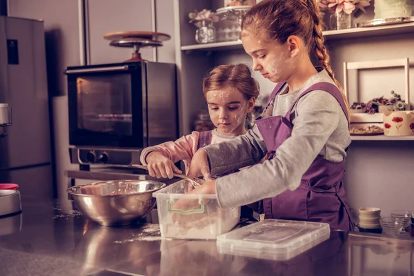 Nette ernsthafte Mädchen bereiten gemeinsam einen Kuchen zu — Stockfoto