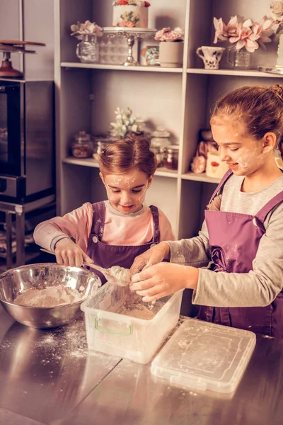 Fröhliche nette Kinder, die versuchen, einen Kuchen zu backen — Stockfoto