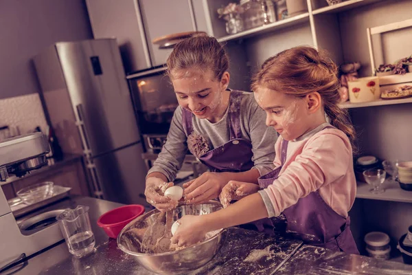 Glada lyckliga flickor att lägga ägg i degen — Stockfoto