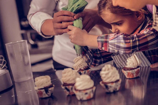 Nice concentrated girl looking at the cupcake