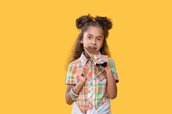 Ευχάριστη αφρο αμερικανικό κορίτσι απολαμβάνοντας σοκολάτα γάλακτος — Φωτογραφία Αρχείου