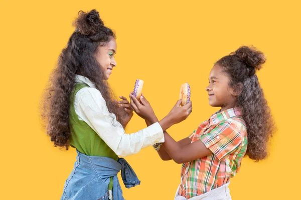 Joyful happy sisters showing each other donuts — Stock Photo, Image