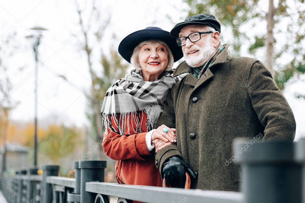 Good mood. Attractive mature woman keeping smile on her face and looking at her husband