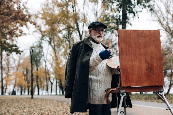 Zralé malíř vytváří krajinu obrázek v parku — Stock fotografie