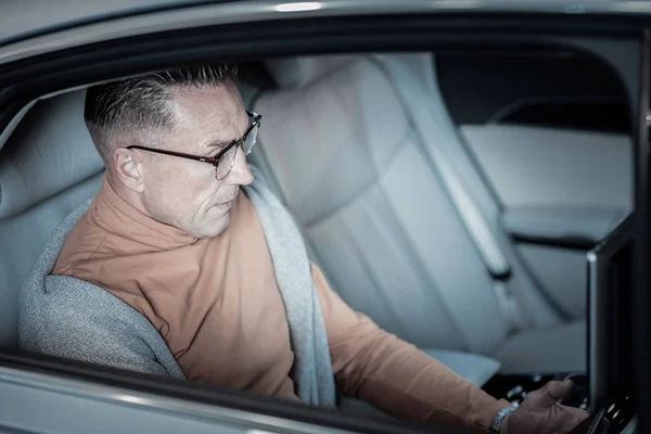 Hombre de negocios rico trabajando en el ordenador portátil mientras está sentado en la parte posterior del coche — Foto de Stock