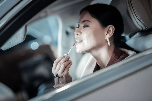 Maduro elegante empresária colorir ela lábios sentado ao volante — Fotografia de Stock