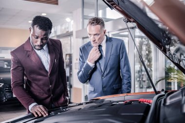 İstemci ve araba yakın koyu kırmızı ceket ayakta giyen satış müdürü