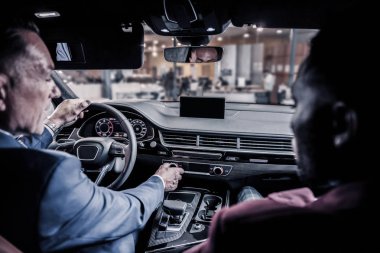 Gelecekteki arabasının direksiyonuna oturan olgun zengin işadamı