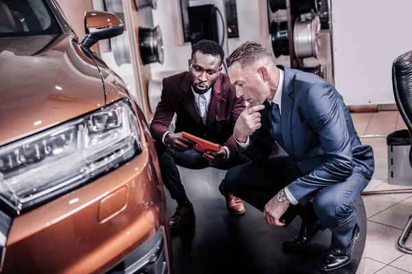 Välmående affärsman bär mörk kostym som funderar på att köpa bil — Stockfoto