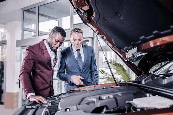 Les hommes d'affaires debout près du coffre avant ouvert pensant à acheter une voiture — Photo
