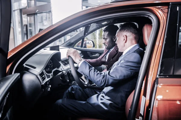 Affärspartners som sitter i nya bilen stående i bil showroom — Stockfoto