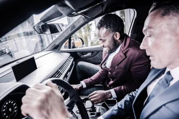 Gerente de ventas barbudo sonriendo mientras consultaba a su cliente sobre el coche — Foto de Stock