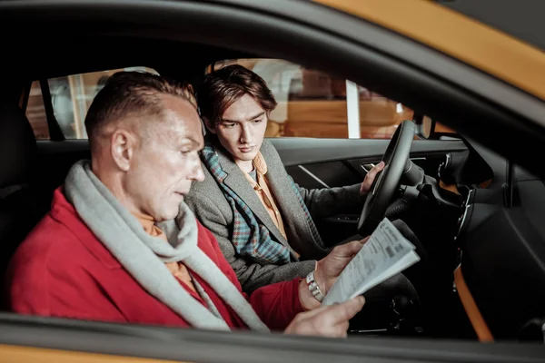 Красивый светловолосый отец читает технические характеристики автомобиля — стоковое фото