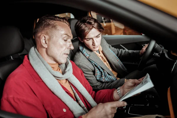 Padre e hijo estudiando la información sobre el coche antes de comprar — Foto de Stock