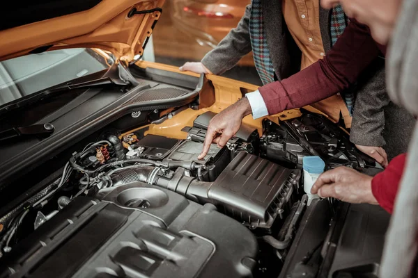 Top view of car salon representative telling his clients about engine — Stock Photo, Image