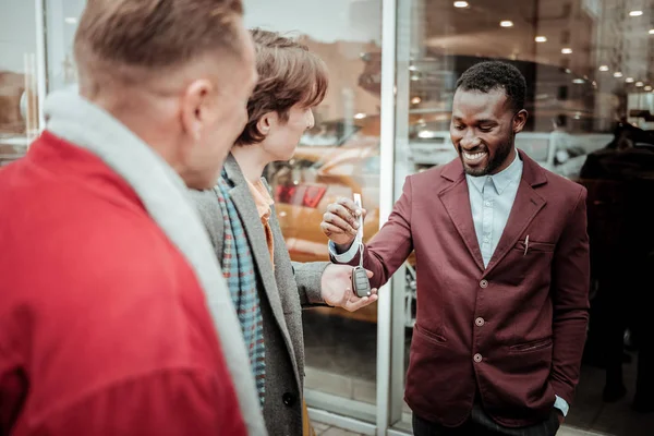 Dark-haired young man taking car keys form smiling sales consultant — Stock Photo, Image