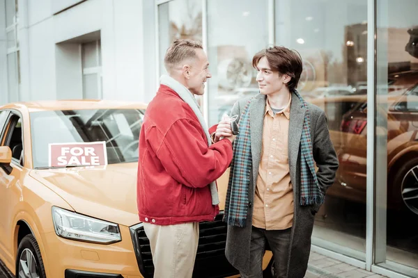 Joven hombre elegante con camisa naranja y abrigo gris mirando a padre — Foto de Stock