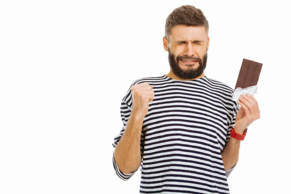 Leuke jonge man probeert niet te eten van chocolade — Stockfoto