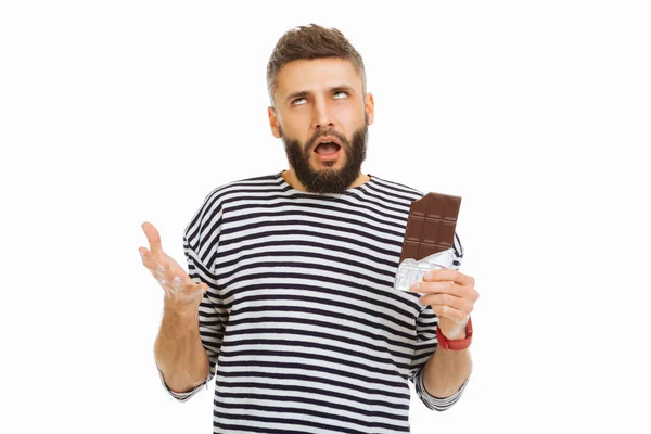 Un uomo scettico che tiene in mano una tavoletta di cioccolato — Foto Stock