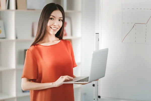 Glimlachende zakenvrouw donker-eyed bedrijf laptop in handen — Stockfoto