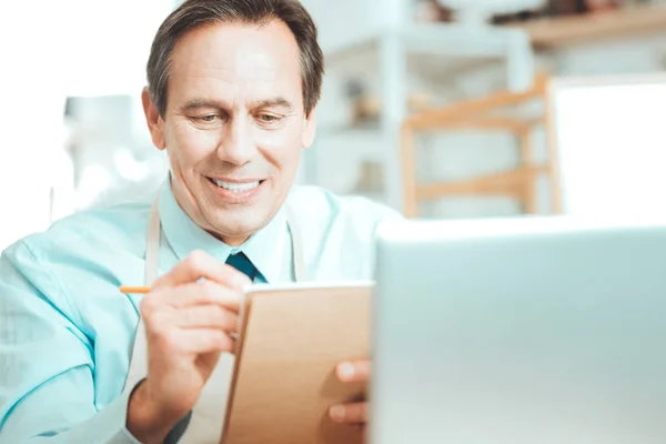 Sonriente hombre escribiendo algo en papel marrón —  Fotos de Stock