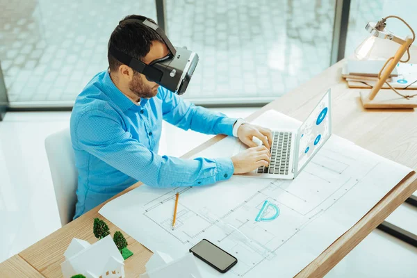 Clever specialist wearing virtual reality glasses and working on the laptop — Stock Photo, Image