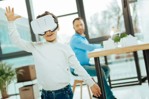 Menino emocional colocando as mãos para cima enquanto usa óculos de realidade virtual — Fotografia de Stock