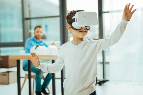 Rapaz inteligente colocando as mãos para cima e usando a realidade virtual — Fotografia de Stock