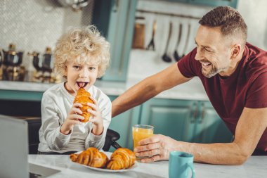 Lezzetli kruvasan ısırma sevimli kara gözlü kıvırcık çocuk