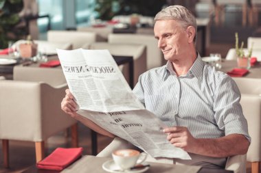 Rahat bir kafede oturan emekli gülümseyen